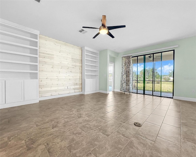 empty room with built in shelves, light tile patterned floors, and ceiling fan