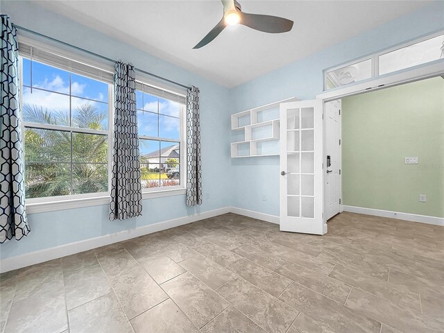 tiled empty room featuring french doors and ceiling fan