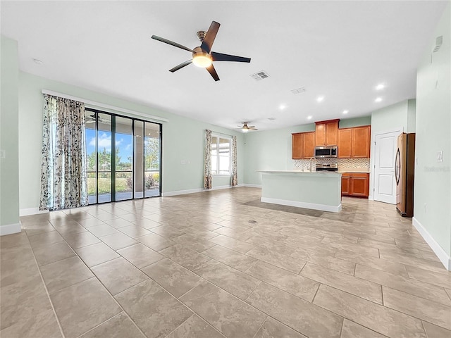 interior space featuring visible vents, brown cabinetry, open floor plan, a center island, and stainless steel appliances