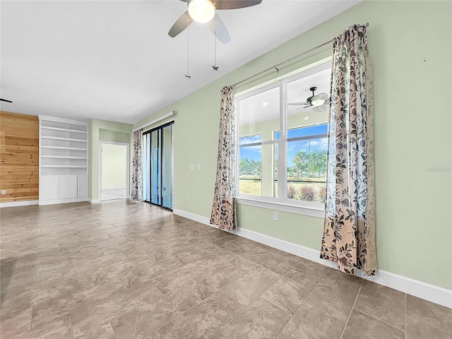 unfurnished room featuring ceiling fan, built in features, and baseboards