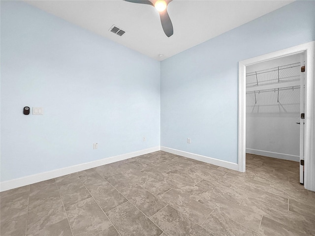 unfurnished bedroom featuring a closet, a walk in closet, visible vents, and baseboards