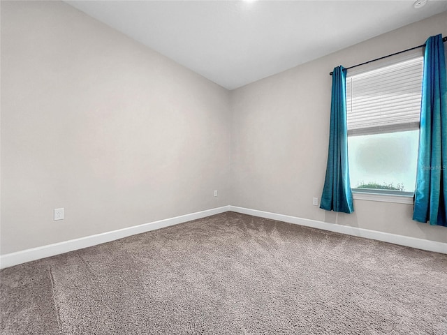 spare room featuring carpet flooring and baseboards