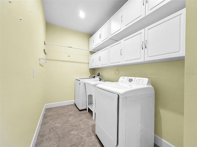 clothes washing area with separate washer and dryer, cabinet space, and baseboards