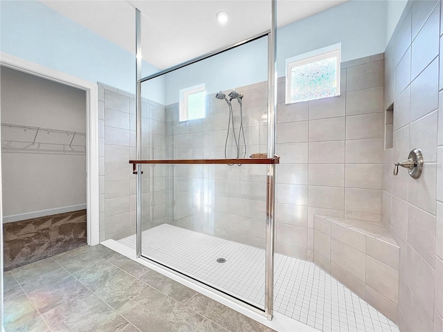 bathroom featuring a tile shower, baseboards, and a walk in closet