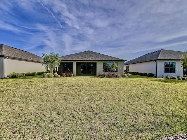 rear view of property with a lawn and stucco siding