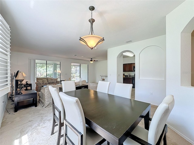 dining space with light carpet and ceiling fan