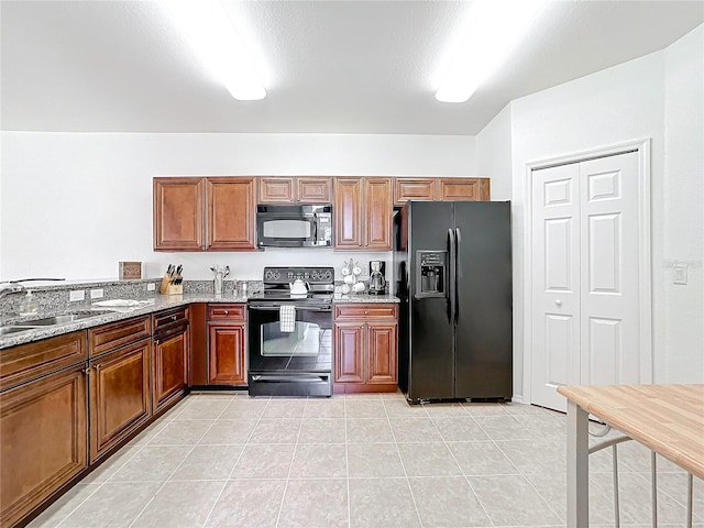 kitchen with black appliances, light stone counters, light tile patterned floors, and sink