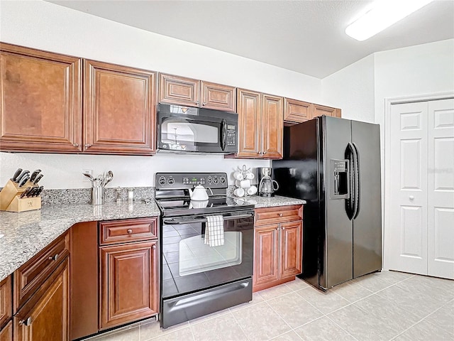 kitchen featuring light stone countertops, light tile patterned flooring, and black appliances