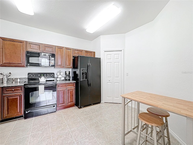 kitchen with black appliances, light stone countertops, and light tile patterned floors