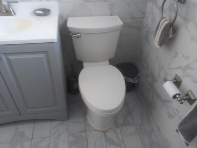 bathroom featuring vanity, toilet, and tile walls