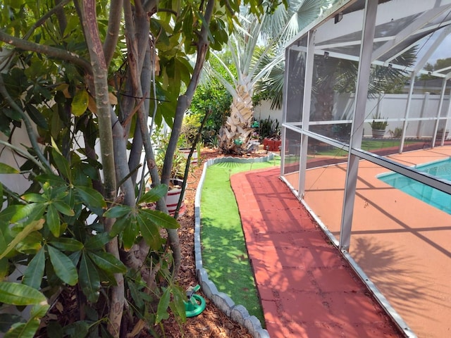 view of yard featuring glass enclosure, a fenced in pool, and a patio