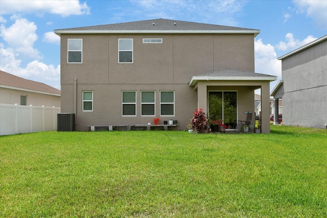 rear view of house featuring central air condition unit and a lawn