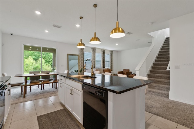 kitchen with light tile floors, sink, dishwasher, hanging light fixtures, and an island with sink