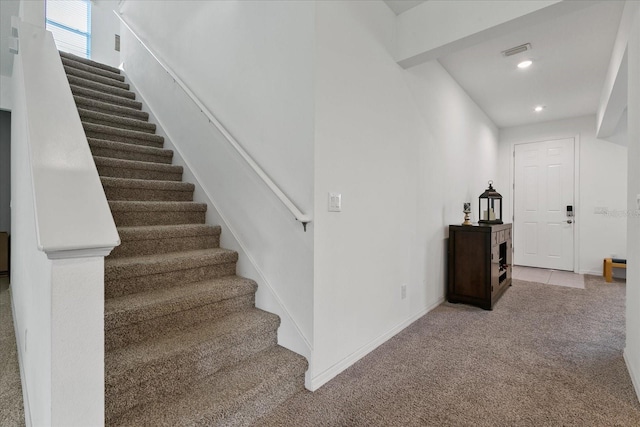 stairway with beamed ceiling and carpet floors