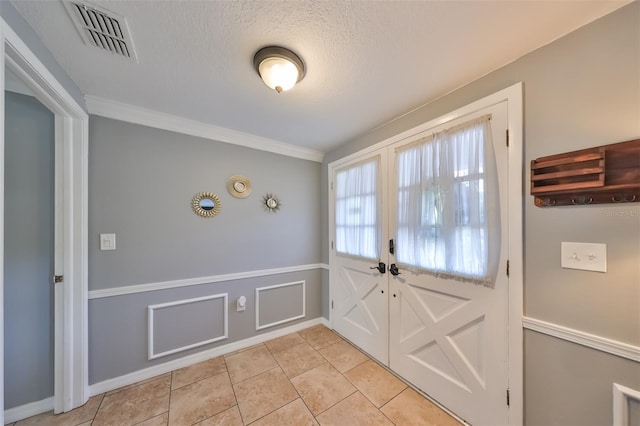 doorway with a textured ceiling, light tile patterned floors, and crown molding