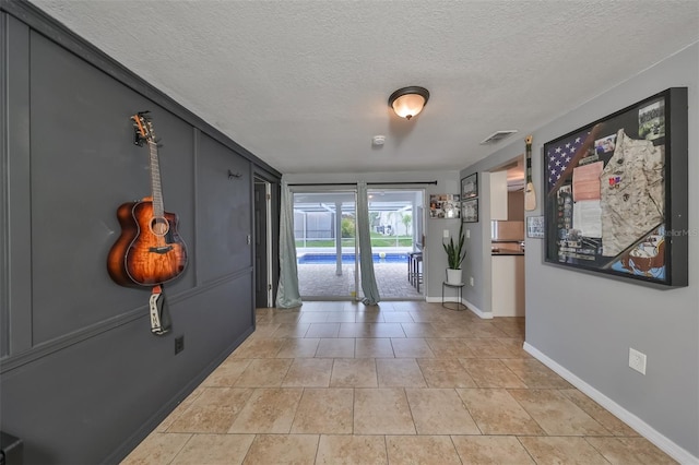 hall with tile patterned floors and a textured ceiling