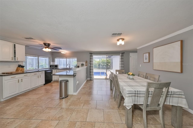 tiled dining room with a textured ceiling, crown molding, sink, and ceiling fan