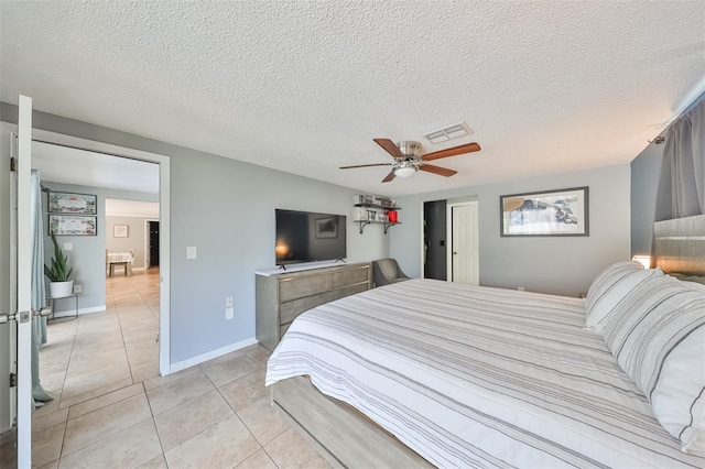 bedroom with ceiling fan, light tile patterned floors, and a textured ceiling