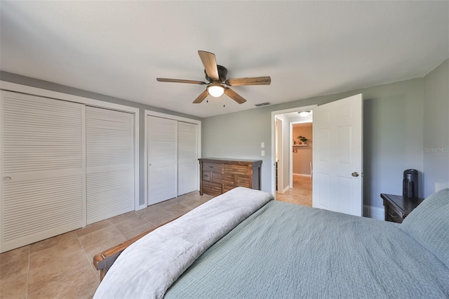 tiled bedroom with multiple closets and ceiling fan