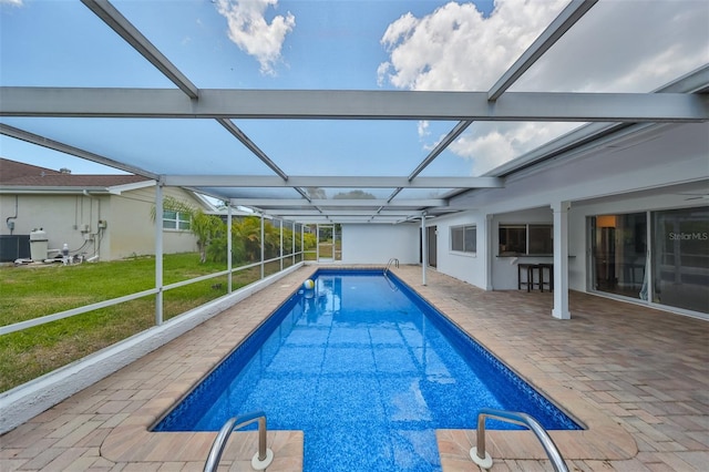 view of pool with a patio, a yard, and glass enclosure