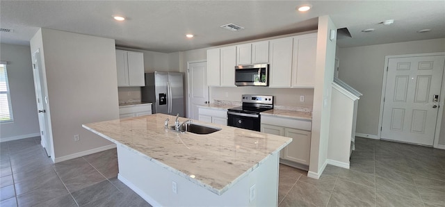 kitchen featuring stainless steel appliances, a center island with sink, sink, and white cabinetry