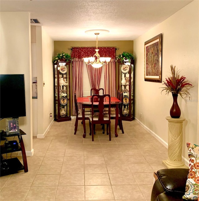 dining space with a textured ceiling, tile flooring, and a notable chandelier