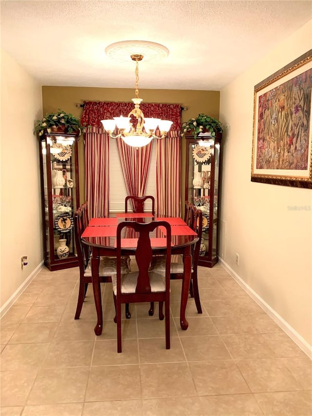 tiled dining room featuring a notable chandelier and a textured ceiling