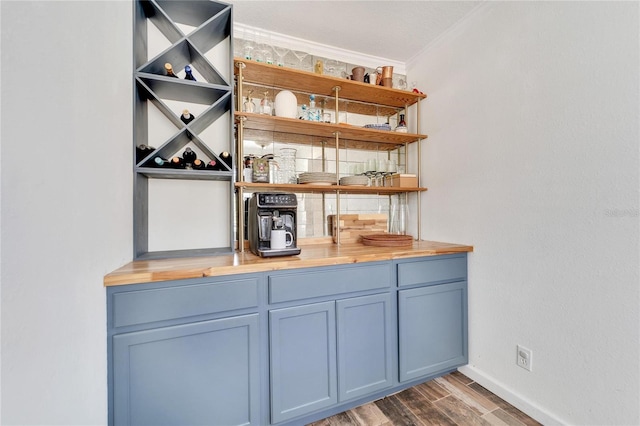 bar featuring crown molding, tasteful backsplash, blue cabinets, and dark hardwood / wood-style floors