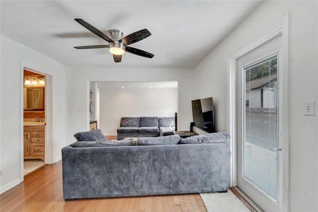 living room featuring sink, light hardwood / wood-style flooring, and ceiling fan