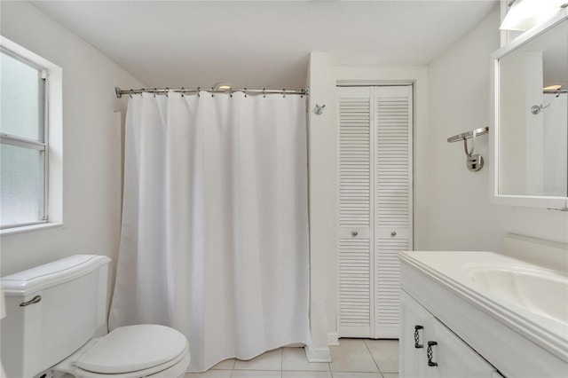 bathroom featuring a healthy amount of sunlight, oversized vanity, toilet, and tile flooring