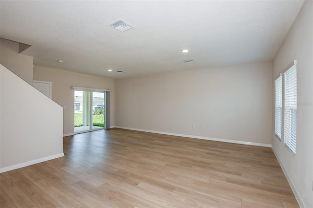 spare room featuring a textured ceiling and light wood-type flooring