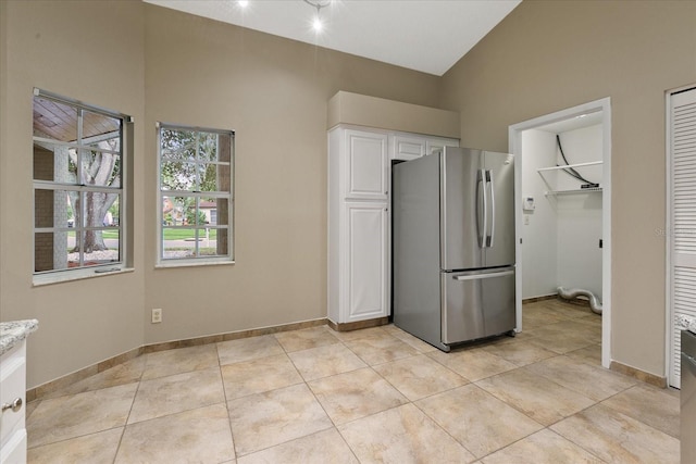 unfurnished bedroom featuring lofted ceiling, light tile floors, and stainless steel fridge