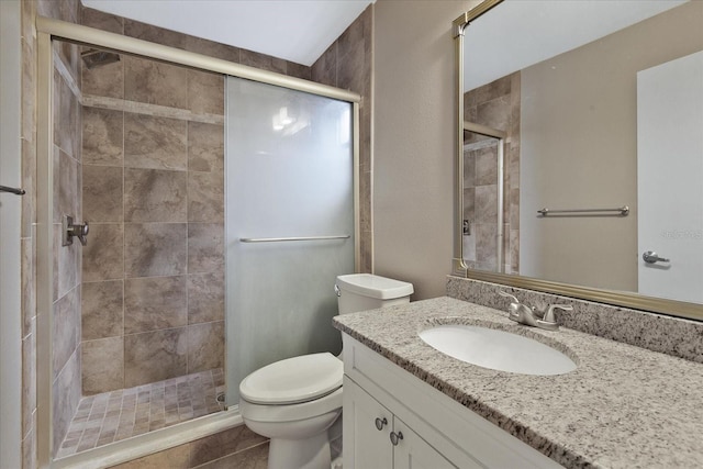 bathroom with a shower with shower door, vanity with extensive cabinet space, toilet, and tile flooring