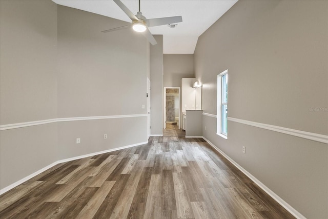 spare room with hardwood / wood-style flooring, high vaulted ceiling, and ceiling fan