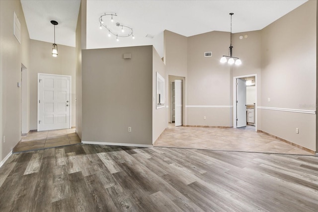 foyer entrance with hardwood / wood-style floors, a towering ceiling, and an inviting chandelier