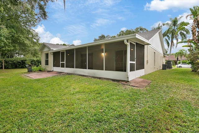 rear view of house featuring central AC, a yard, and a sunroom