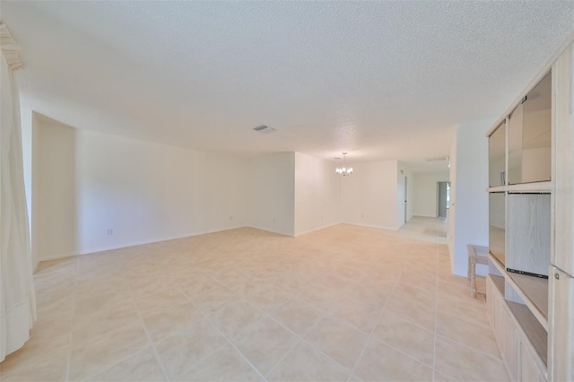 unfurnished room with light tile patterned flooring, a textured ceiling, and a chandelier