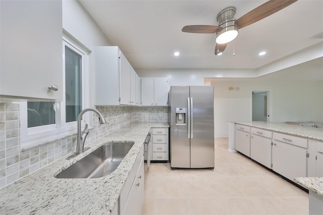 kitchen with ceiling fan, decorative backsplash, white cabinets, sink, and stainless steel fridge