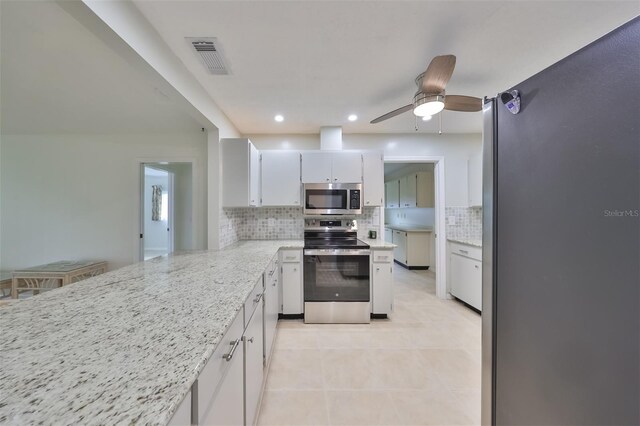 kitchen with ceiling fan, decorative backsplash, white cabinets, light tile patterned floors, and stainless steel appliances