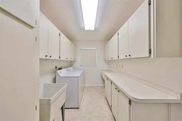 washroom with washer and clothes dryer, cabinet space, light tile patterned flooring, a sink, and a textured ceiling