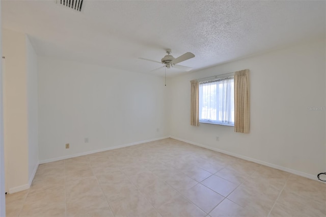 spare room featuring a textured ceiling, ceiling fan, and light tile patterned flooring