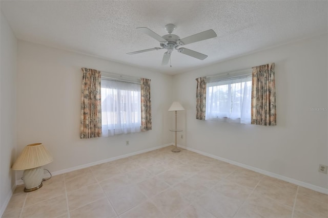 tiled empty room with ceiling fan and a textured ceiling