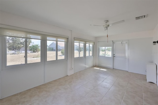 spare room featuring ceiling fan, light tile patterned flooring, and a healthy amount of sunlight