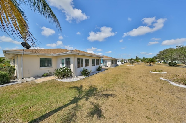 rear view of property with stucco siding and a yard