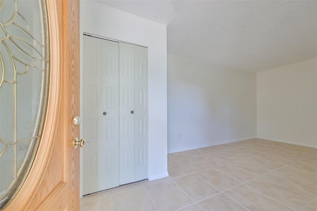 unfurnished bedroom with a closet, a textured ceiling, and light tile patterned floors