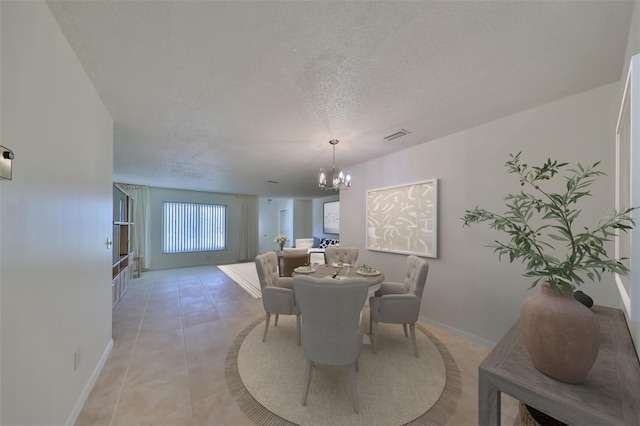 dining space featuring a textured ceiling, an inviting chandelier, and light tile patterned flooring