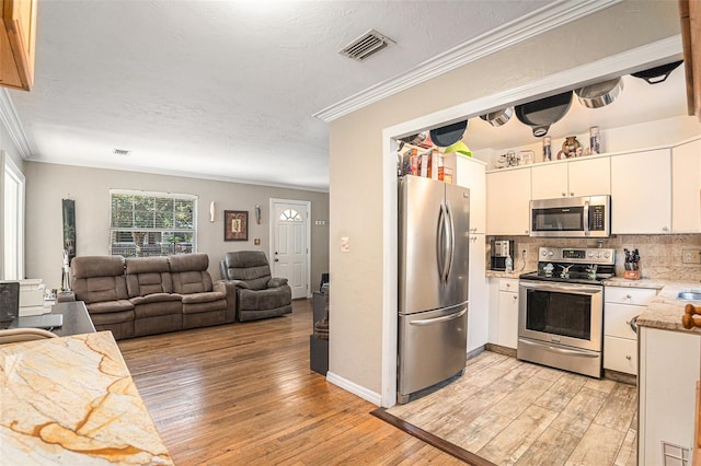 kitchen with crown molding, light hardwood / wood-style flooring, white cabinetry, backsplash, and stainless steel appliances