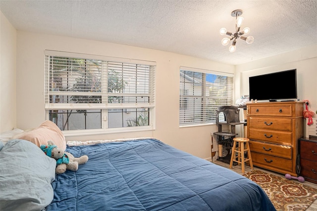 bedroom with an inviting chandelier, a textured ceiling, and multiple windows