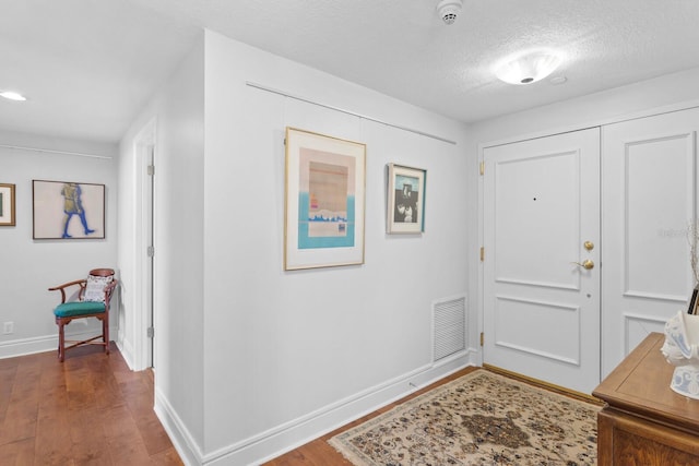 foyer entrance with dark wood-type flooring and a textured ceiling