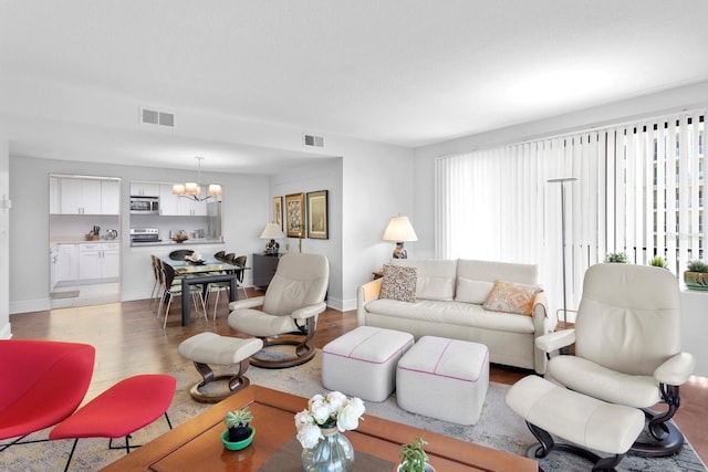 living room featuring plenty of natural light, a chandelier, and light wood-type flooring